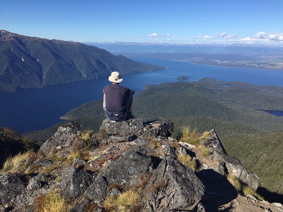 Chris morrison sitting on a rock, looking at the view over Lake Te Anau within the Fiordland National Park